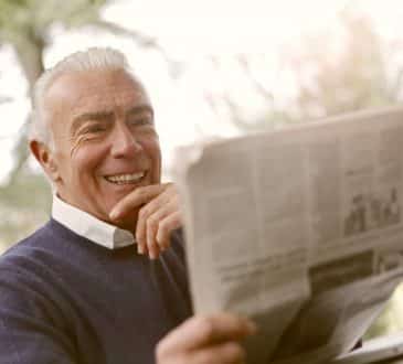 elderly man with newspaper smiling