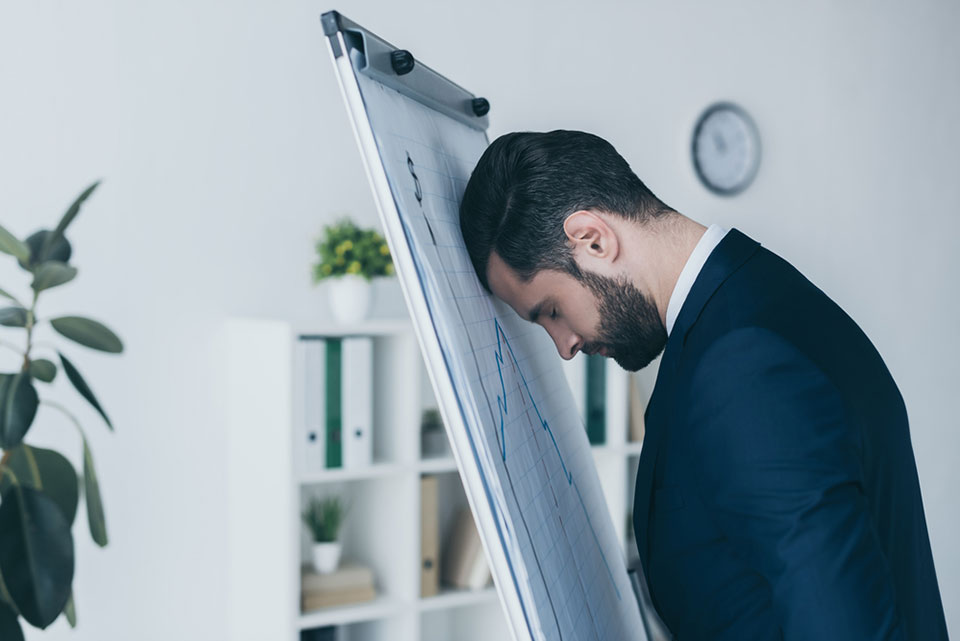 Depressed businessman standing with closed eyes and leaning at flipchart with forehead