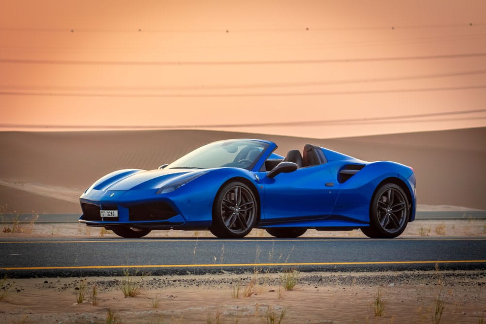 Front view of Ferrari 488 Spider convertible supercar parked on an Abu Dhabi street in the desert at sunset, United Arab Emirates