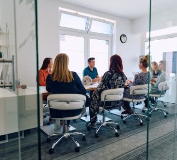 Diverse Business Team Discussing Projects in a Modern Glass Office.