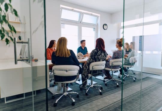 Diverse Business Team Discussing Projects in a Modern Glass Office.