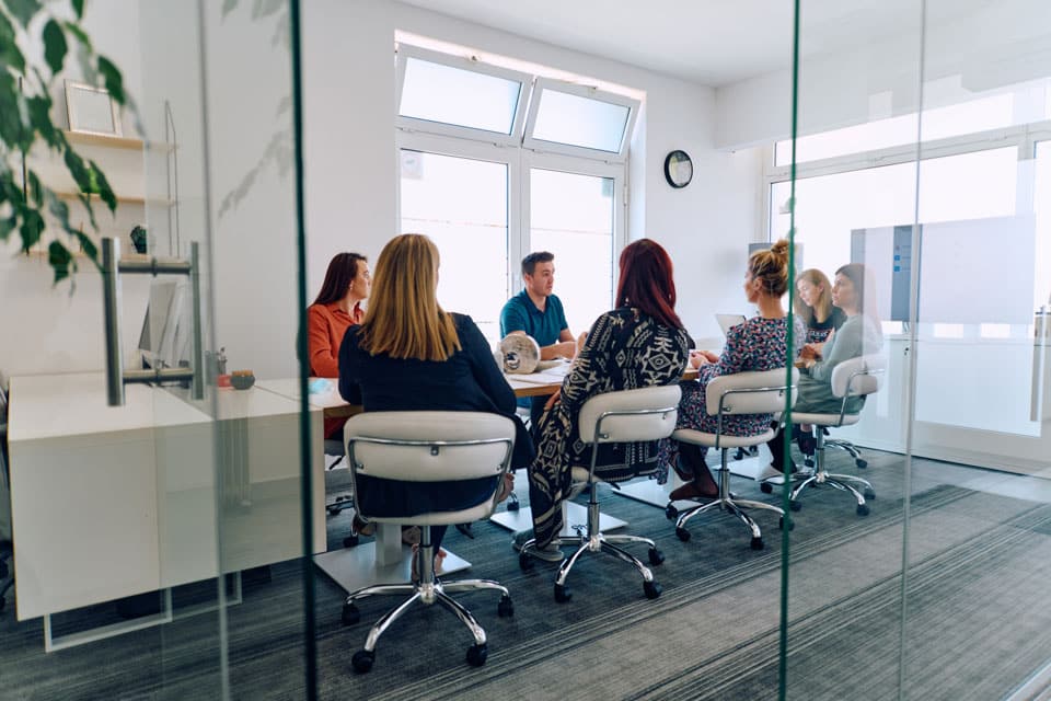 Diverse Business Team Discussing Projects in a Modern Glass Office.